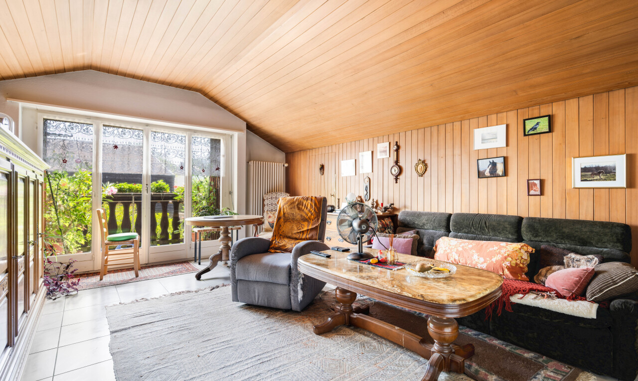 salon avec plafond voûté, vaulted ceiling, mur en bois, wood wall, et sol en carrelage