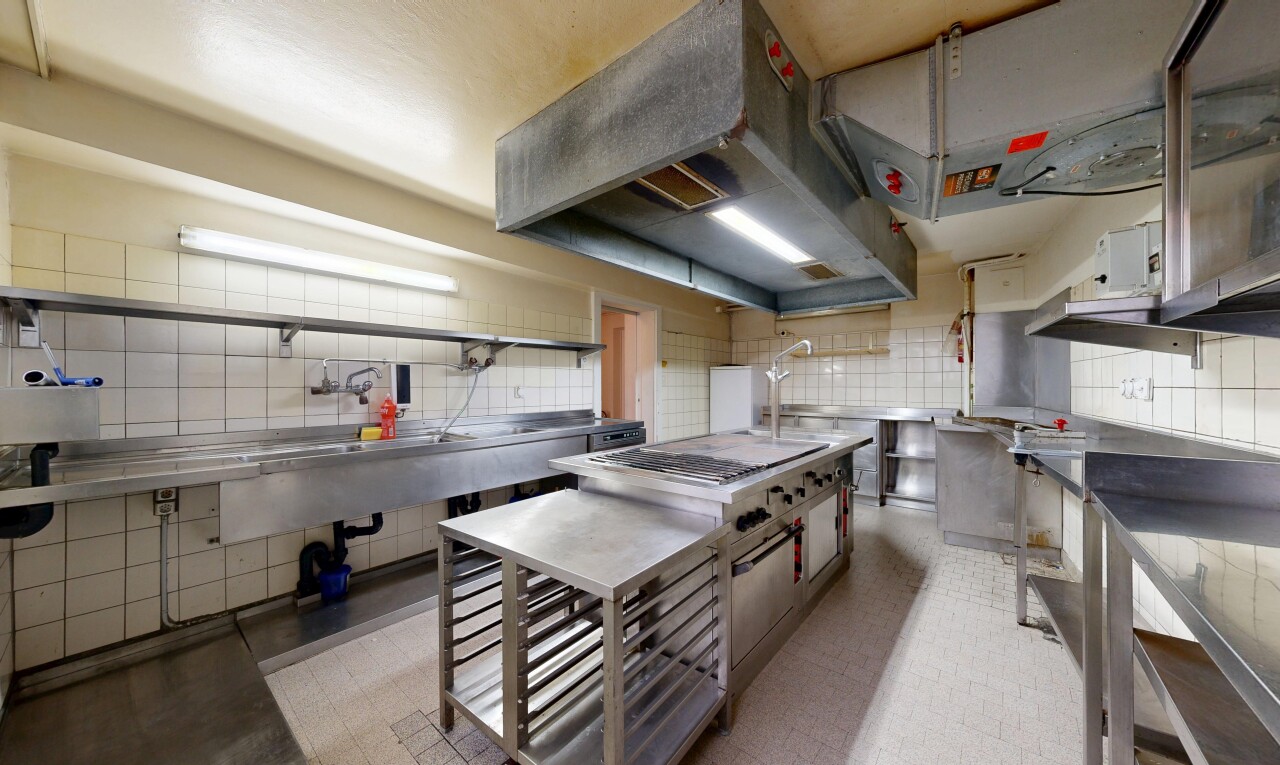 cuisine avec plans de travail en acier inoxydable, hotte, inside property, dosseret, et backsplash