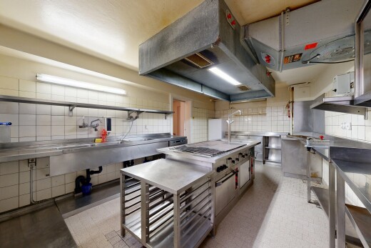 cuisine avec plans de travail en acier inoxydable, hotte, inside property, dosseret, et backsplash