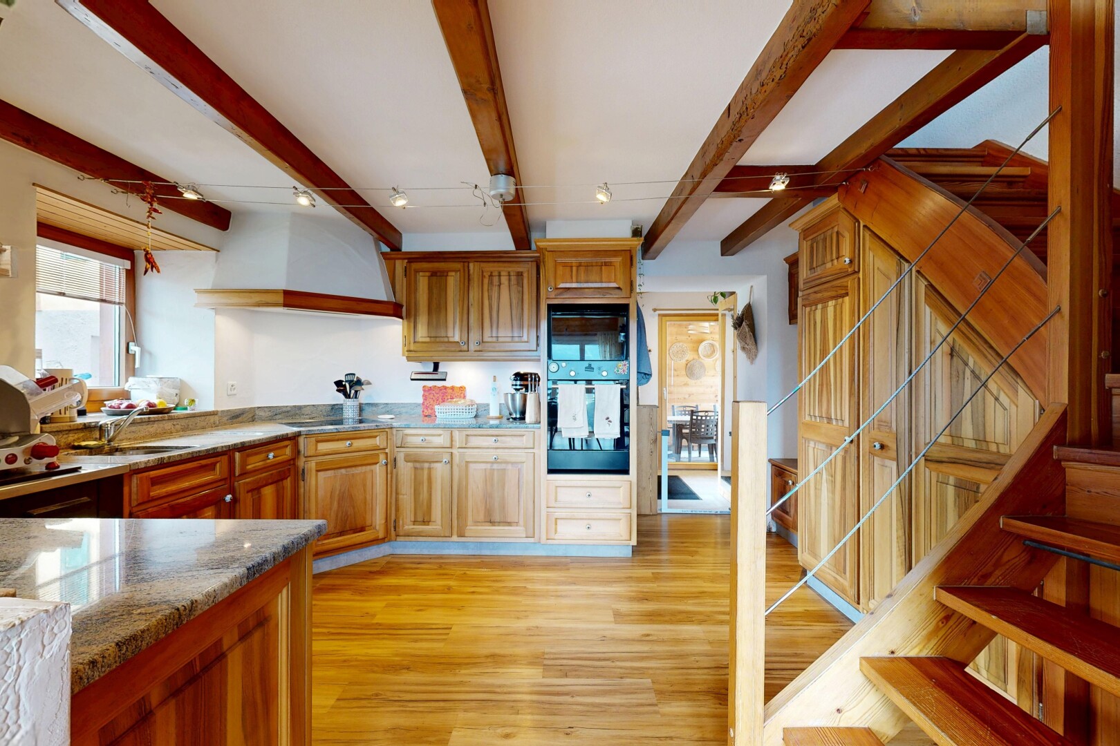 kitchen featuring dark stone counters, oven, light wood-style flooring, wood finish cabinetry, and beamed ceiling