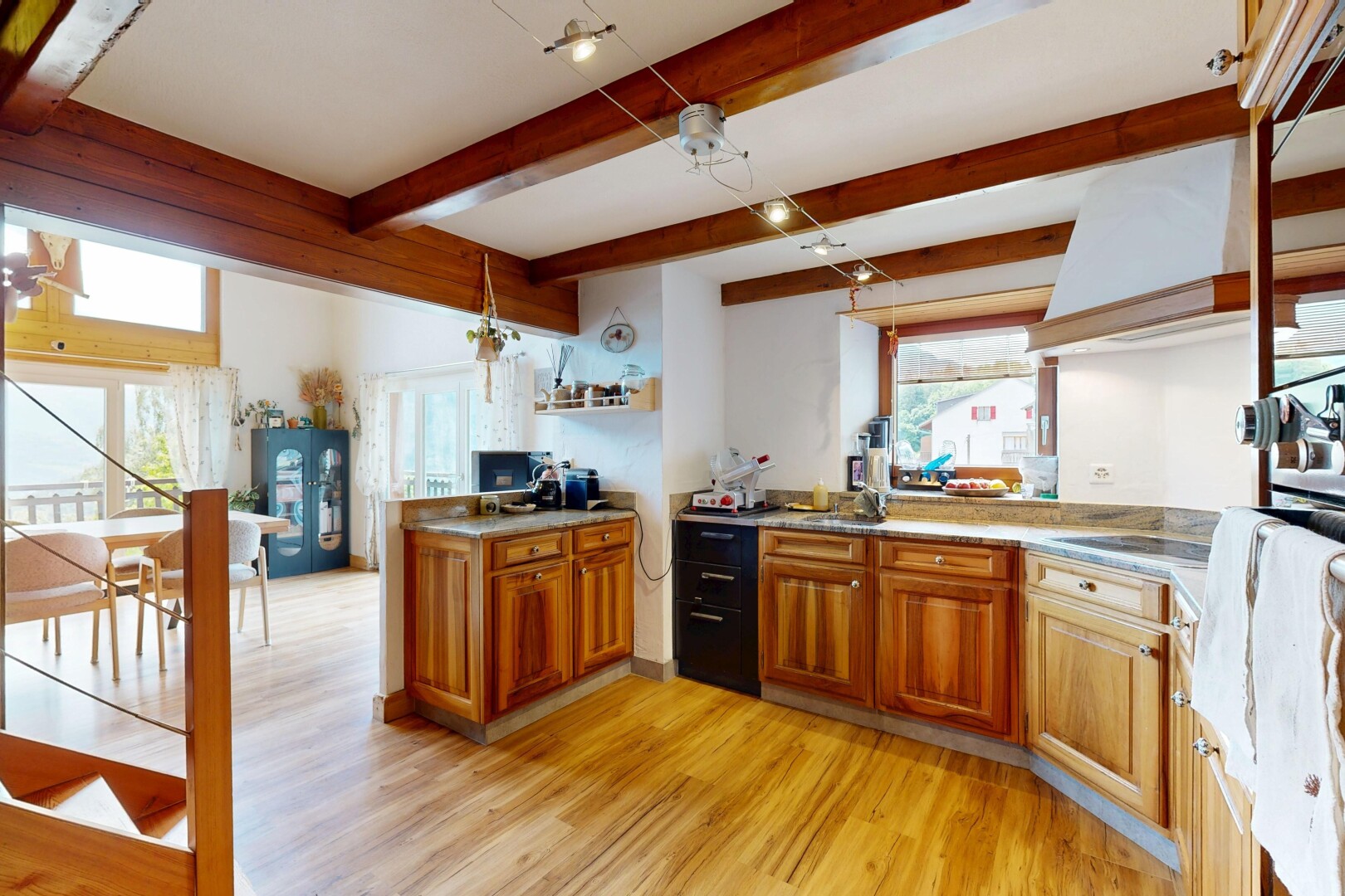kitchen featuring wood finish cabinetry, light wood-type flooring, light countertops, a peninsula, and beam ceiling