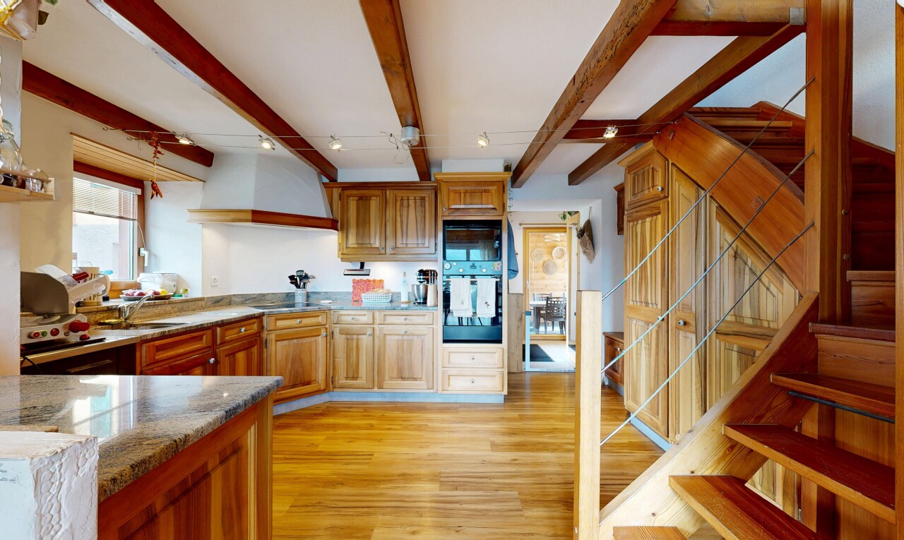 kitchen featuring dark stone counters, oven, light wood-style flooring, wood finish cabinetry, and beamed ceiling