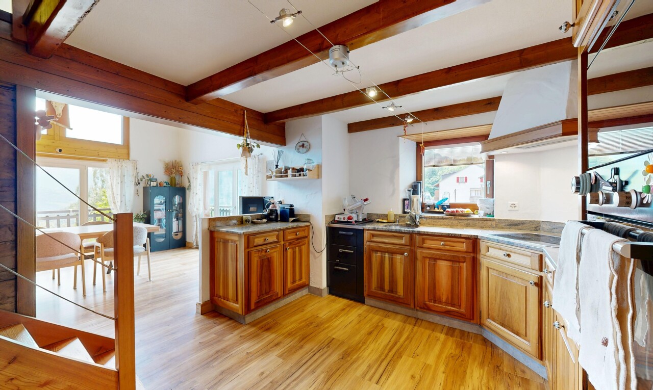 kitchen featuring wood finish cabinetry, light wood-type flooring, light countertops, a peninsula, and beam ceiling
