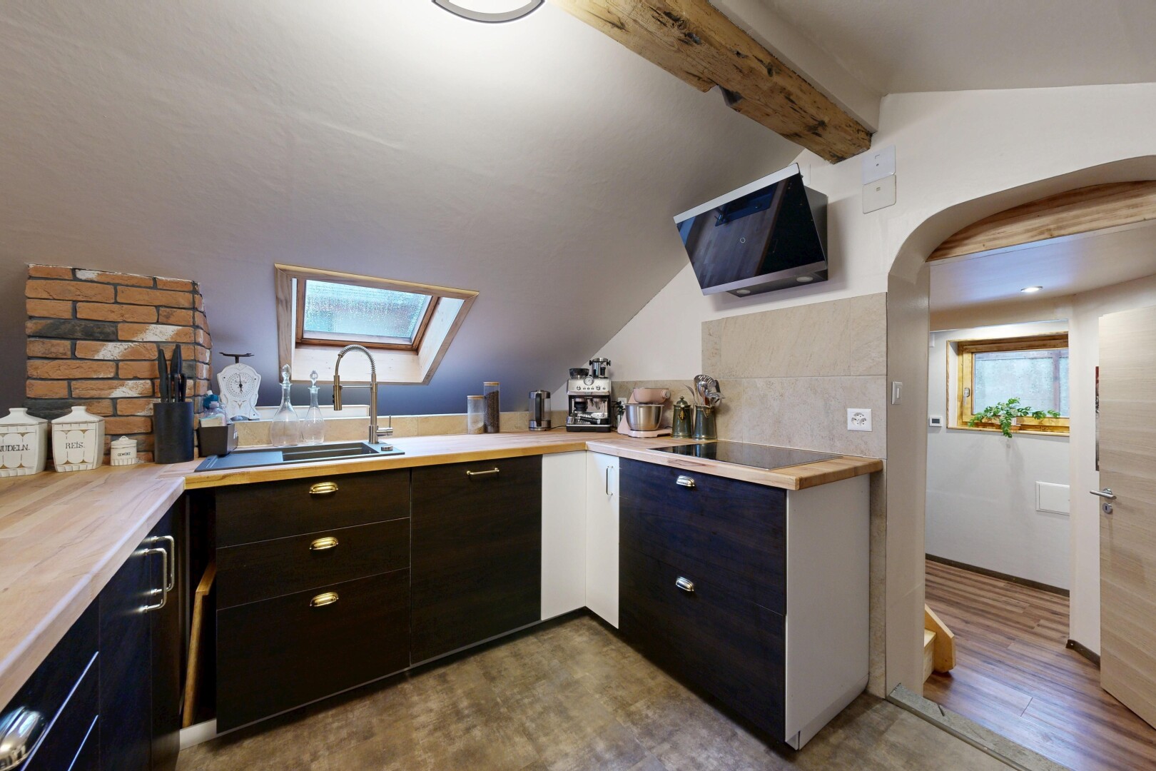 kitchen with a skylight, light countertops, arched walkways, dark wood-style flooring, and black electric cooktop