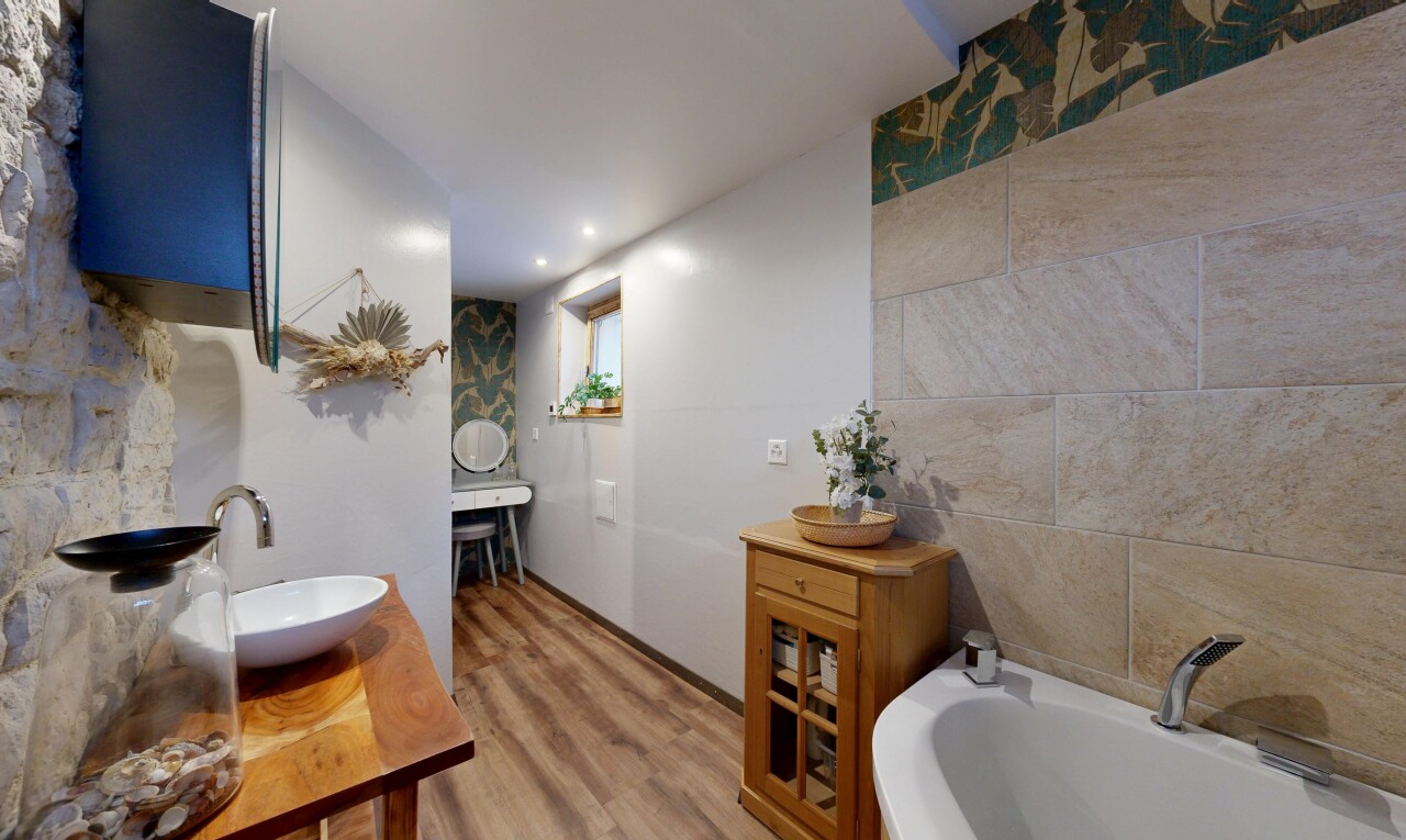 full bath with a garden tub, light wood-style flooring, vanity, and tile walls