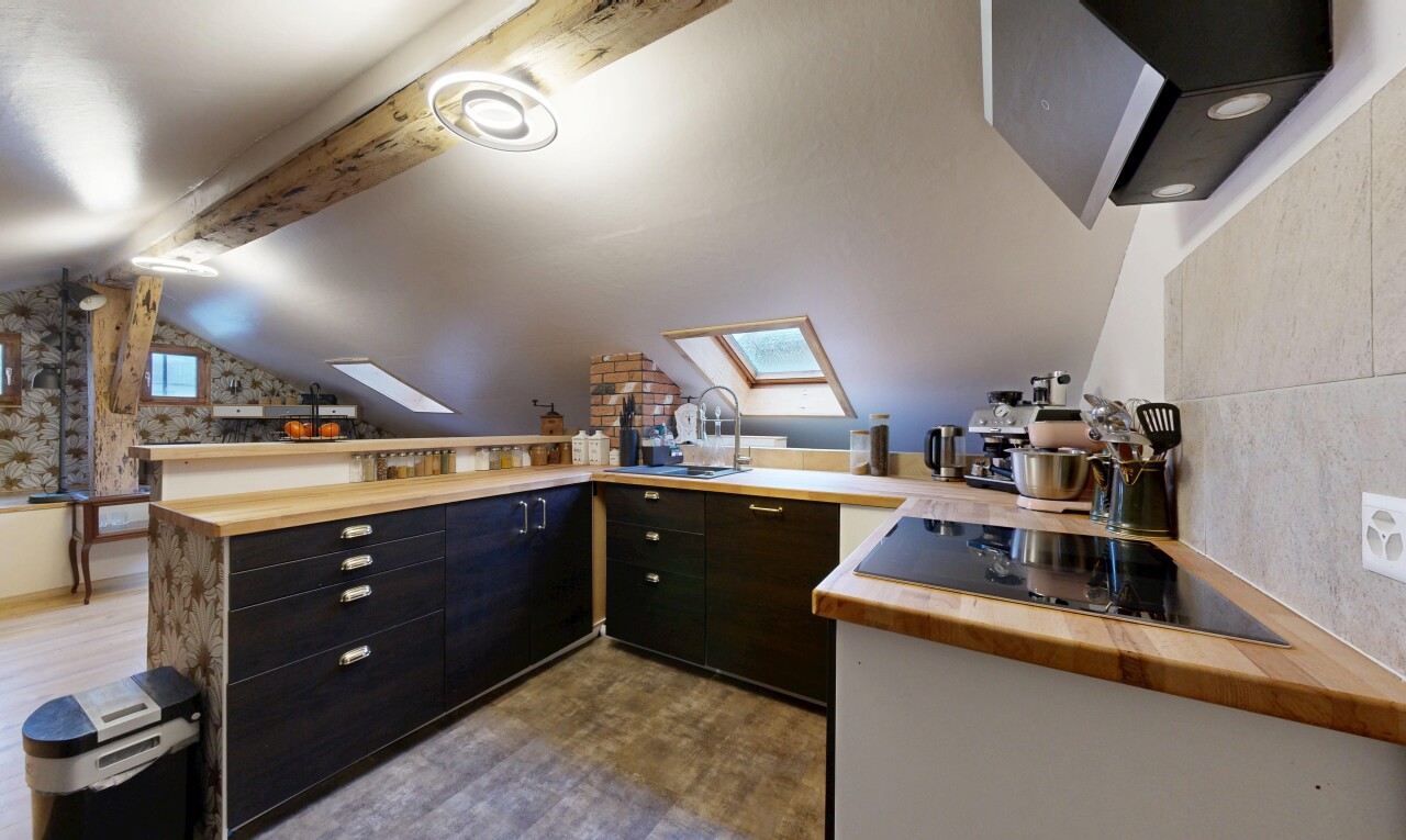 kitchen with range hood, light countertops, a peninsula, a skylight, and lofted ceiling