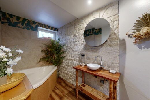 salle de bains avec miroir, bain, salle de bain complète, mur en pierre, et stone wall