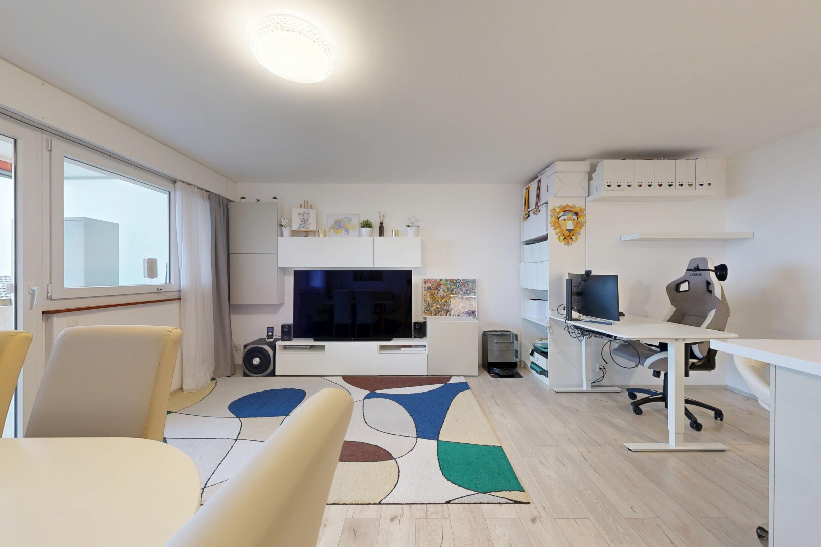 salon avec espace bureau, télévision, wood finish floor, sol en finition bois, et drywall