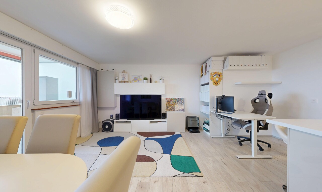 salon avec espace bureau, télévision, wood finish floor, sol en finition bois, et drywall