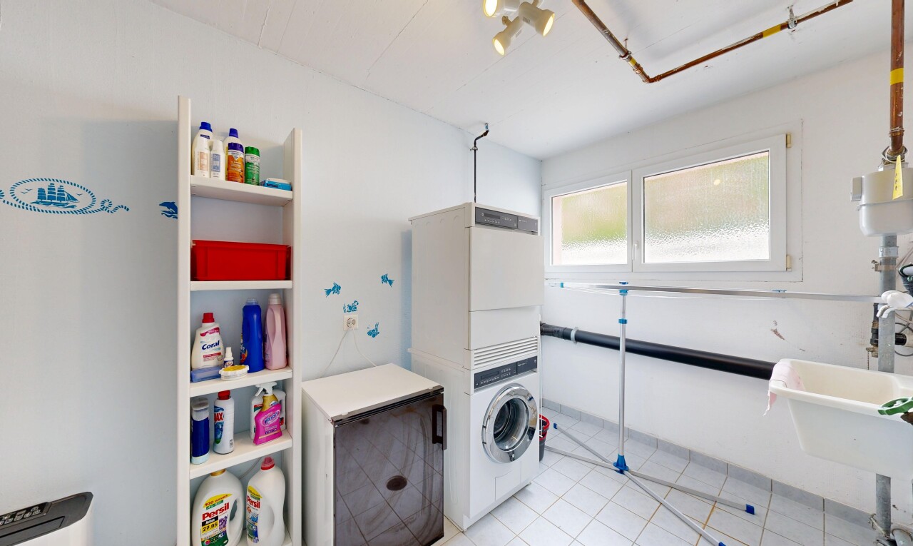 buanderie avec inside property, drywall, cloison sèche, lave-linge et sèche-linge superposés, et light floor