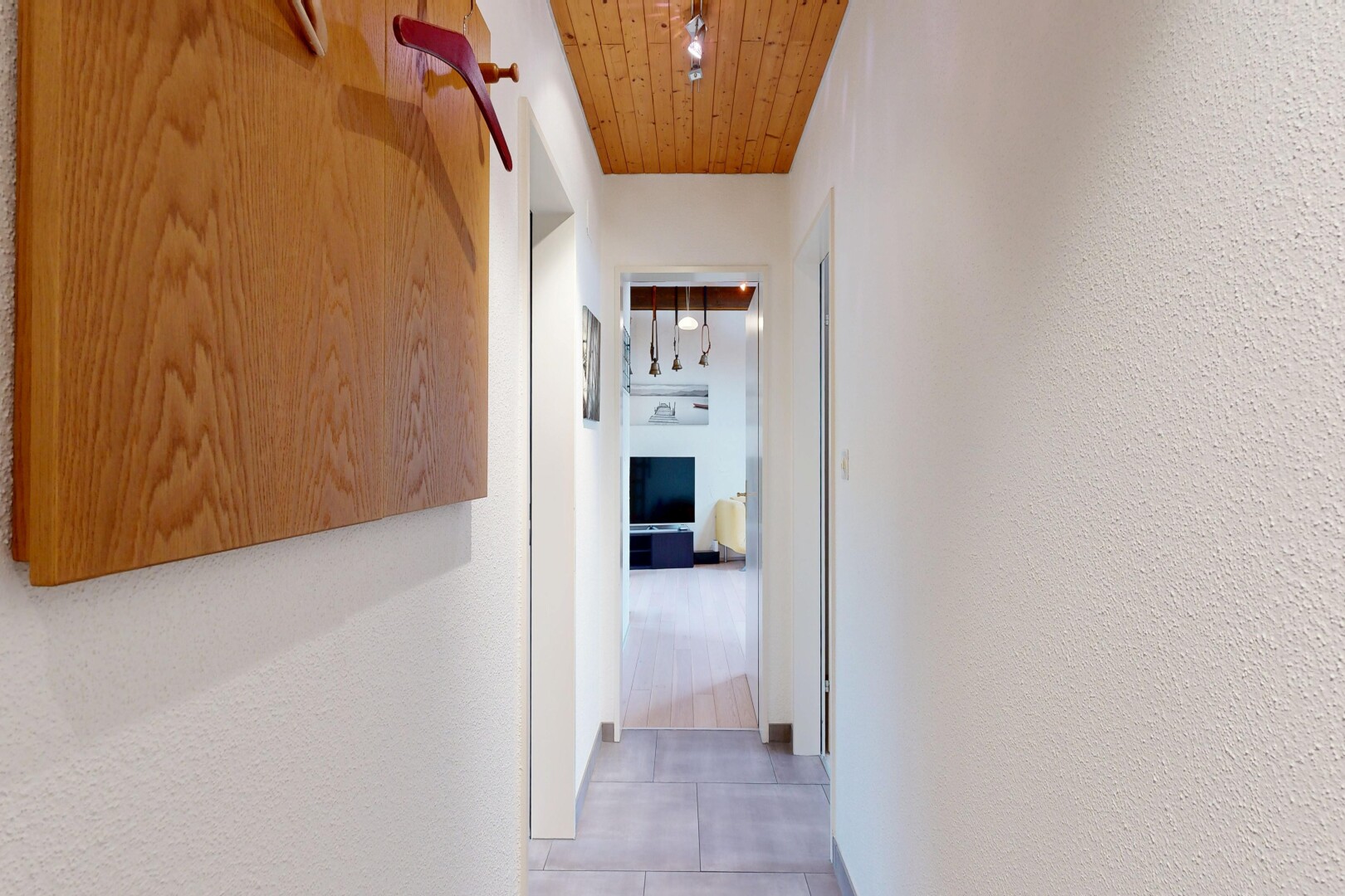 couloir avec plafond en bois, wood ceiling, mur texturé, textured wall, et light floor
