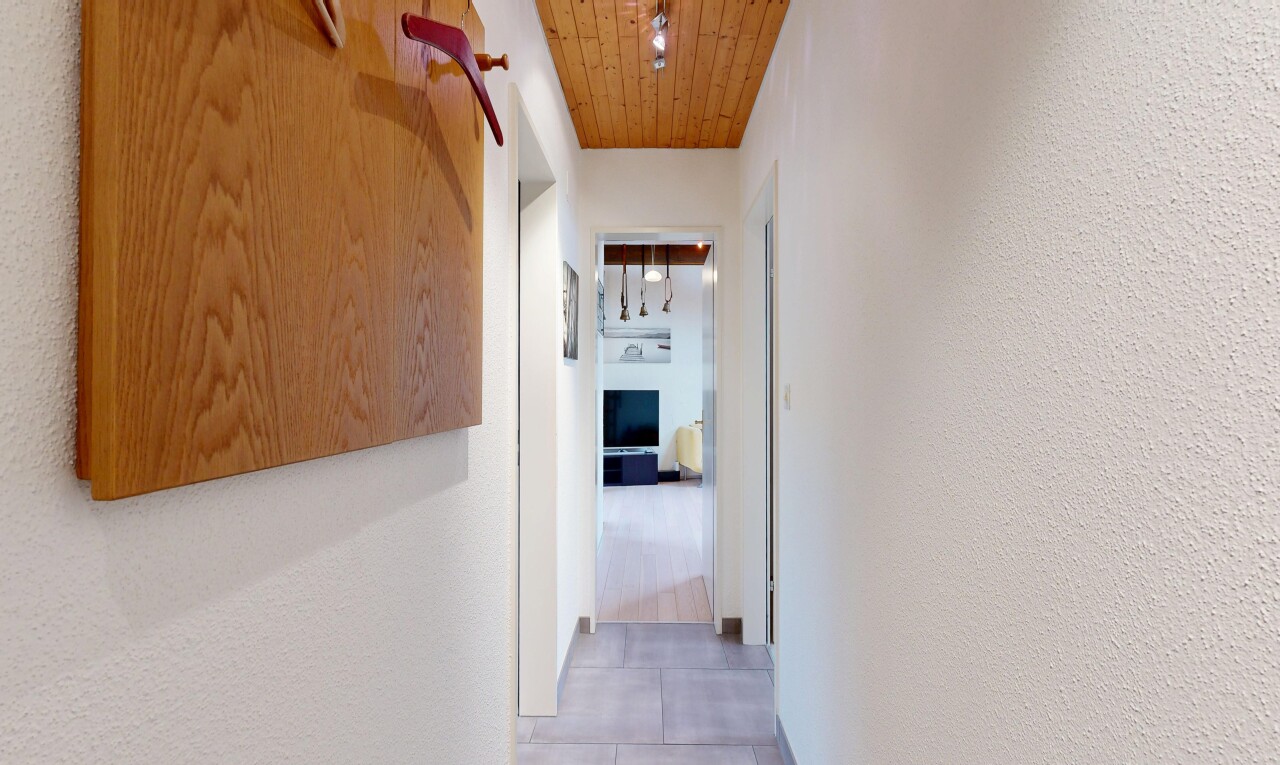 couloir avec plafond en bois, wood ceiling, mur texturé, textured wall, et light floor