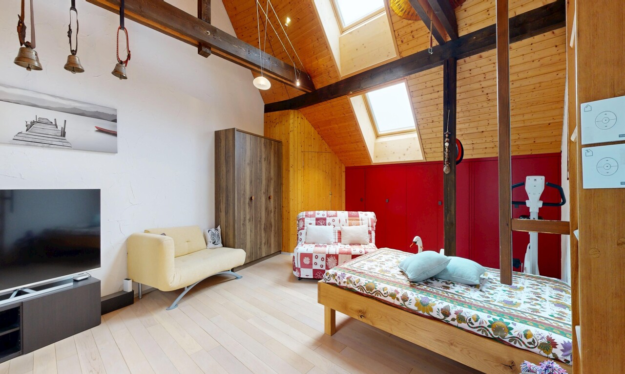 chambre avec puits de lumière, beamed ceiling, plafond à poutres, télévision, et wood finish floor