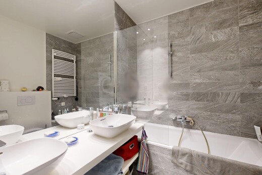 full bathroom featuring radiator heating unit, double vanity, a towel warming rack, tile walls, and tiled shower / bath