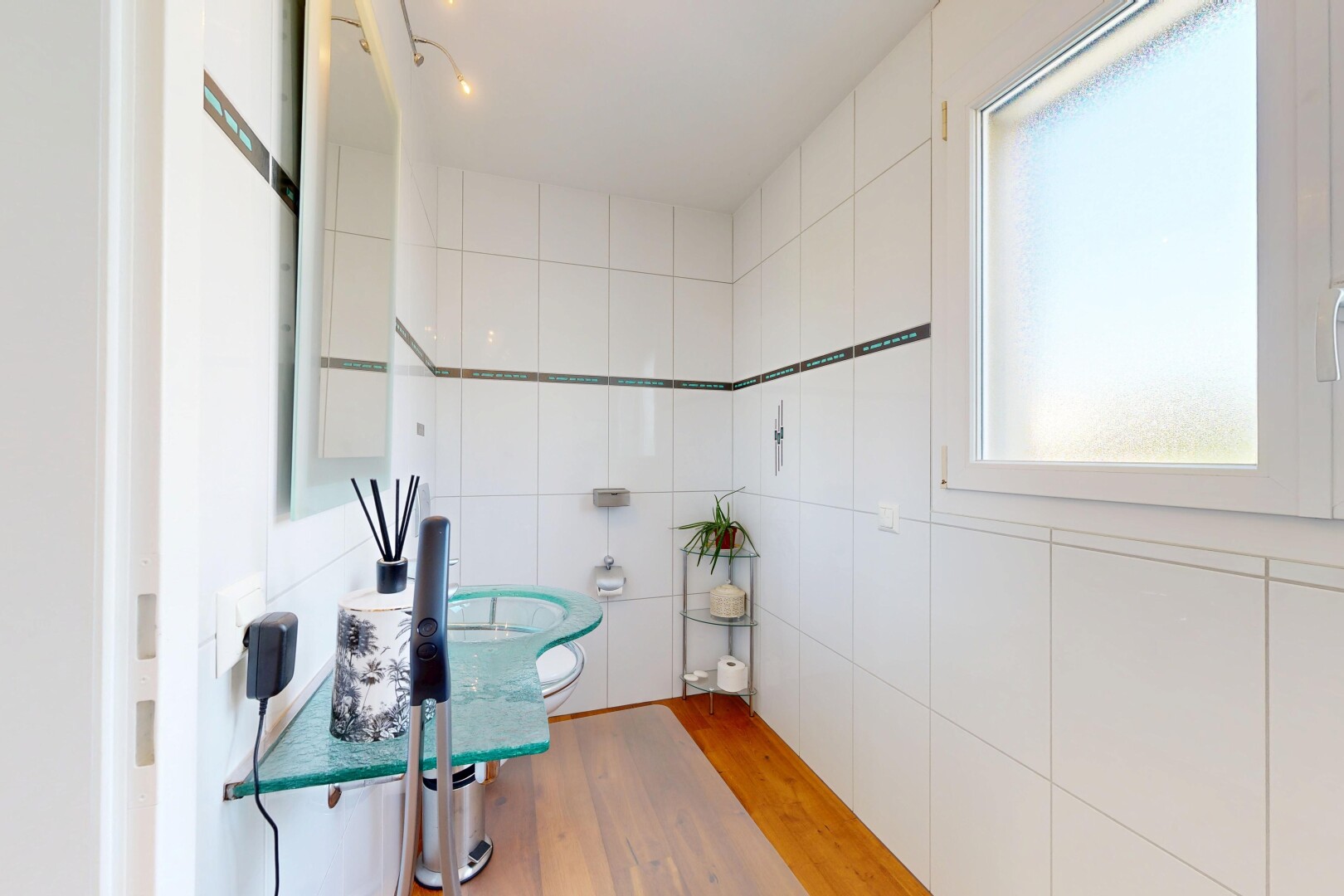 salle de bains avec mur en carrelage, tile wall, miroir, toilette, et sol en finition bois