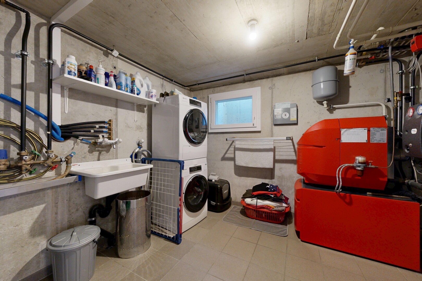 buanderie avec concrete wall, mur en béton, lave-linge et sèche-linge superposés, concrete ceiling, et plafond en béton