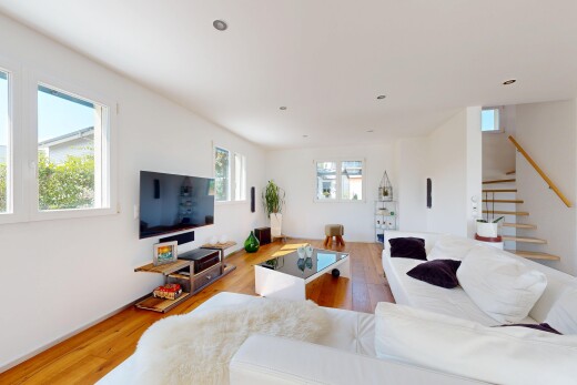 salon avec escaliers, lumière naturelle, télévision, wood finish floor, et drywall