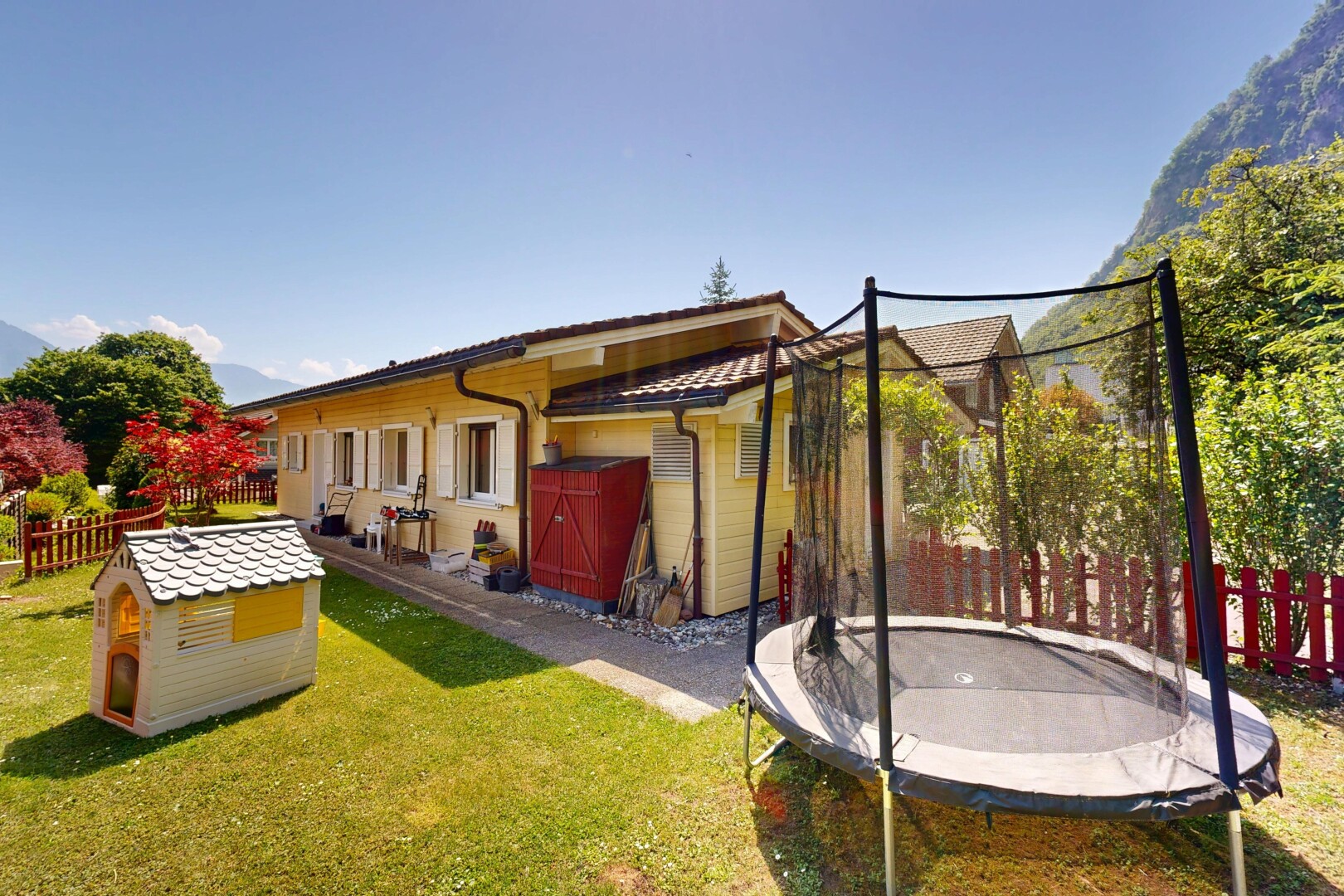 façade avec clôture, trampoline, property visible, pelouse, et day time