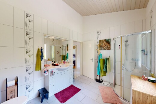 salle de bains avec mur en carrelage, tile wall, lavabo (ou coiffeuse selon le contexte), douche, et salle de bain complète