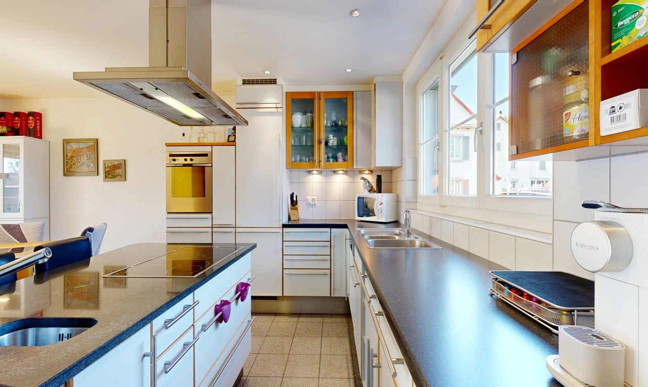 cuisine avec hotte, dark countertops, armoires avec insert en verre, glass insert cabinets, et armoires blanches