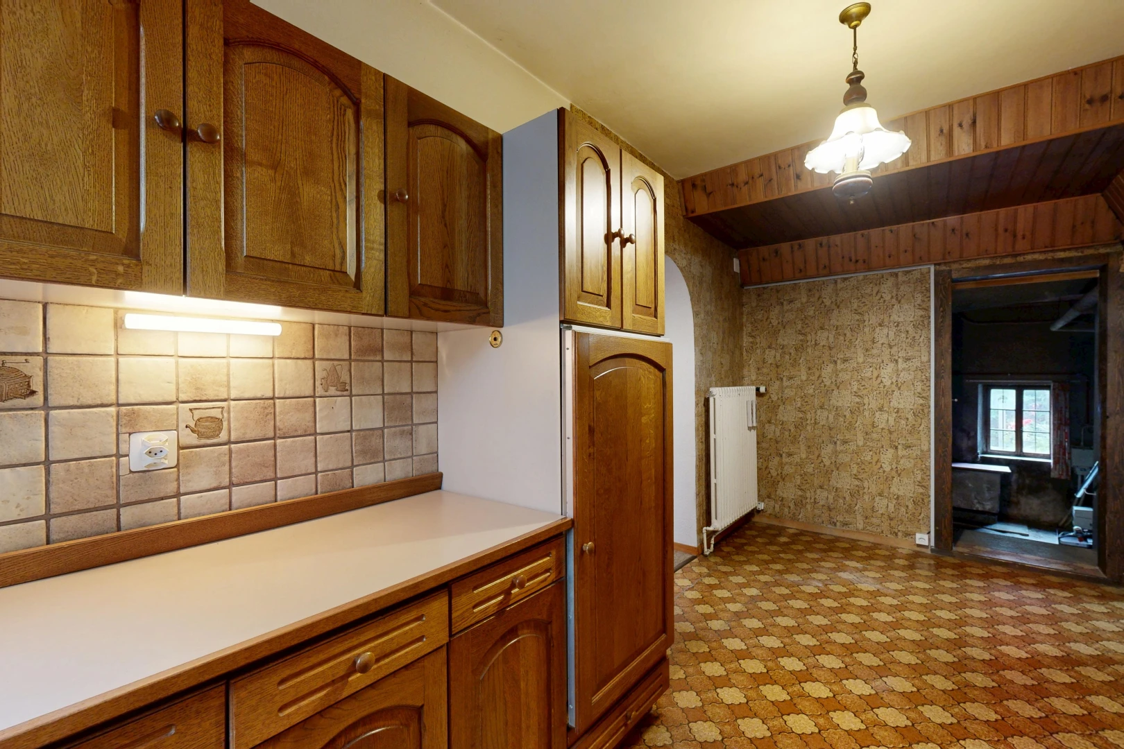 cuisine avec armoires en arc, arched cabinets, plans de travail, light countertops, et armoires marron moyen