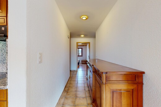 hall featuring light tile patterned floors and a textured wall