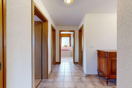 corridor with light tile patterned floors and a textured wall