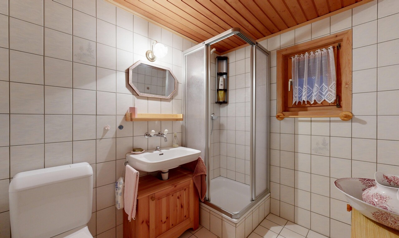 salle de bains avec miroir, douche, lavabo (ou coiffeuse selon le contexte), mur en carrelage, et tile wall