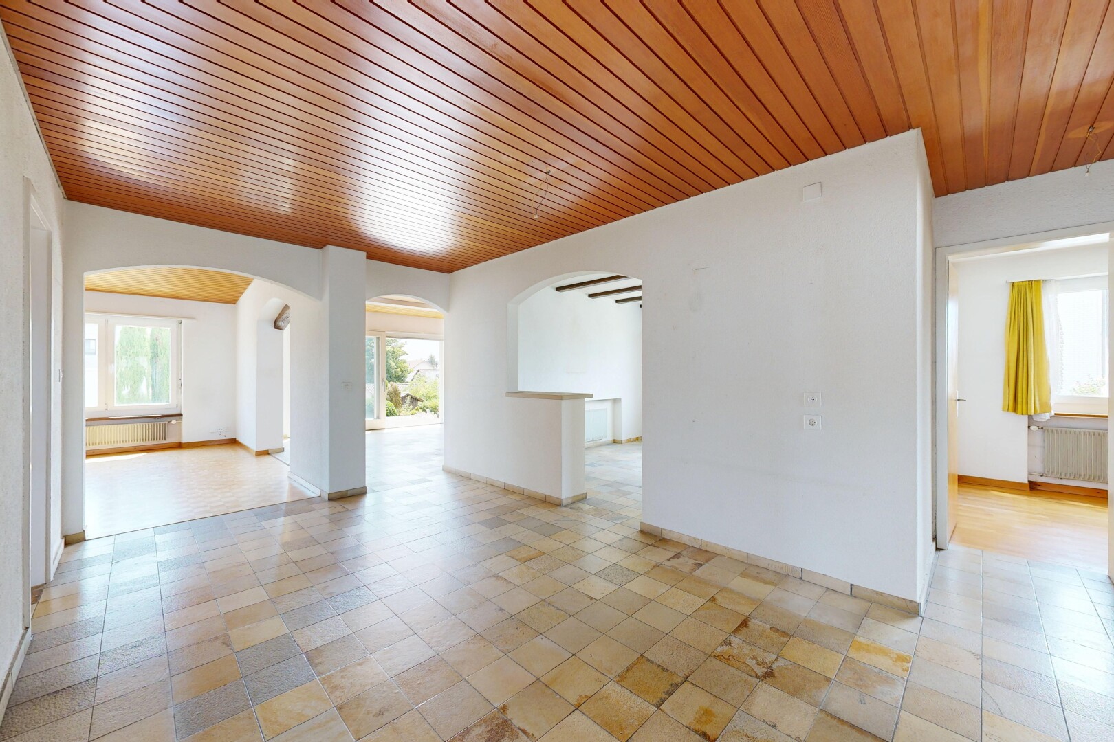 unfurnished room with wood ceiling, radiator heating unit, and arched walkways