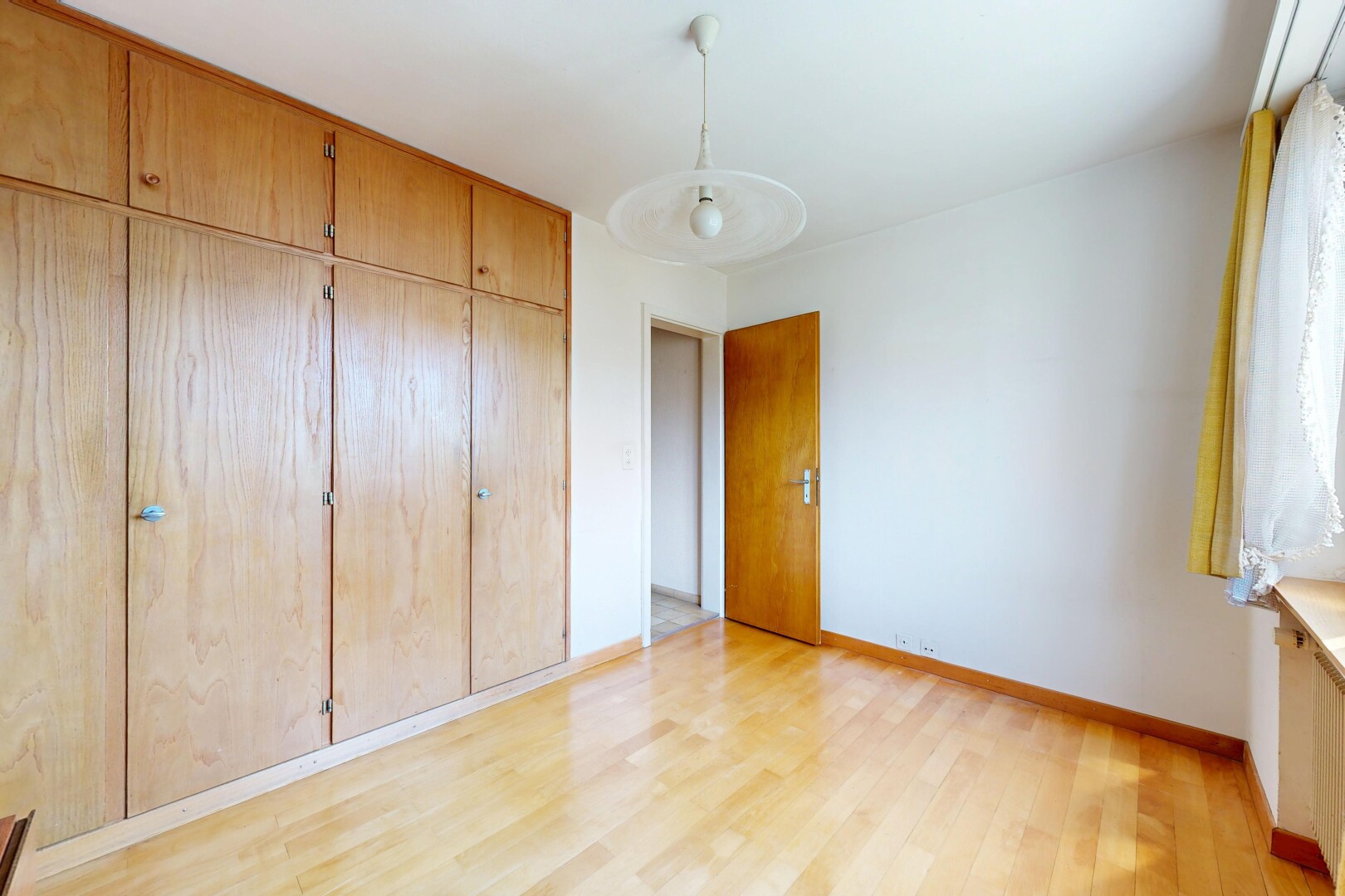 unfurnished room featuring a closet, light wood-type flooring, and hanging light fixtures