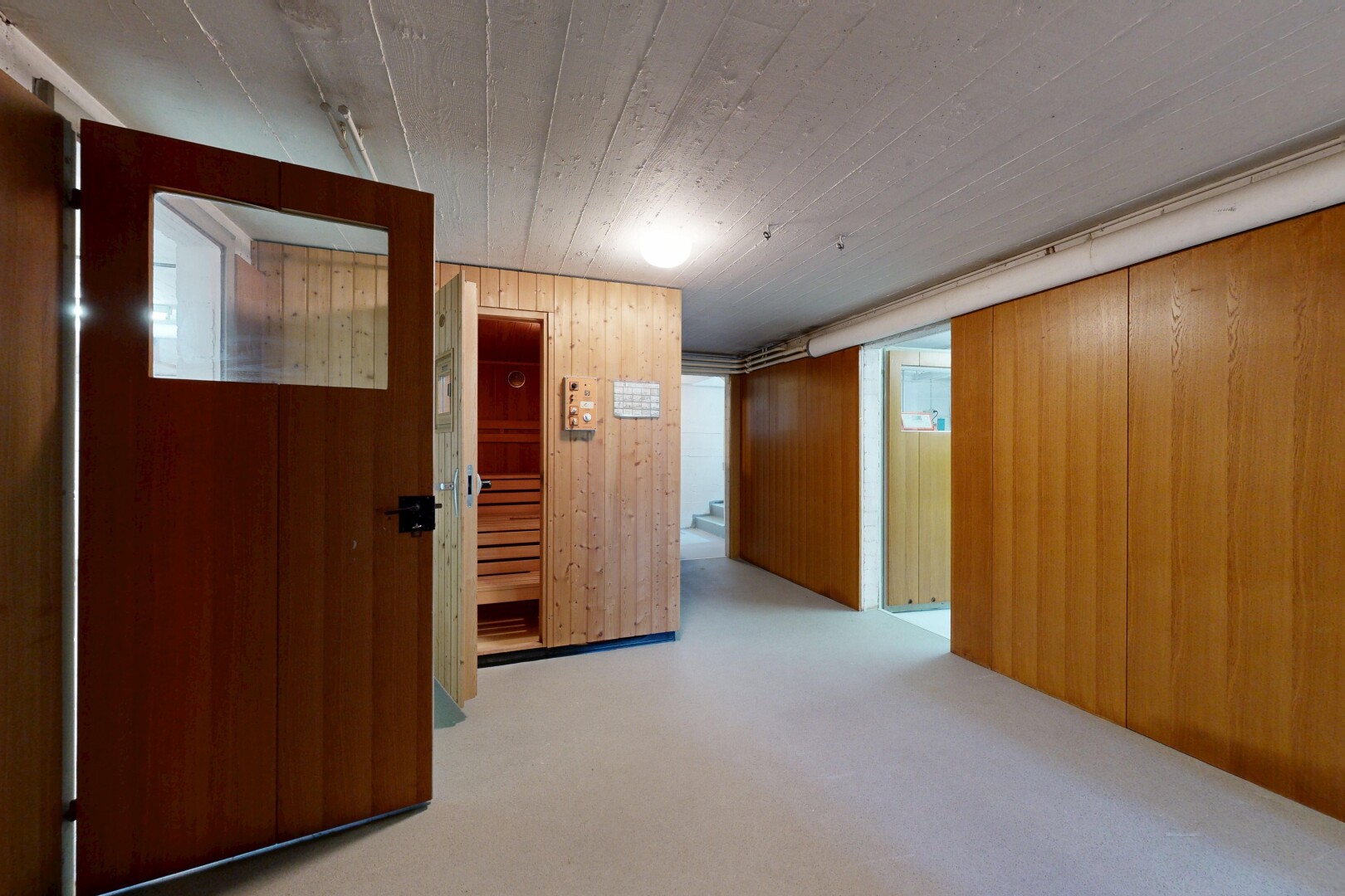 corridor featuring wood walls, a sauna / steam room, and light carpet