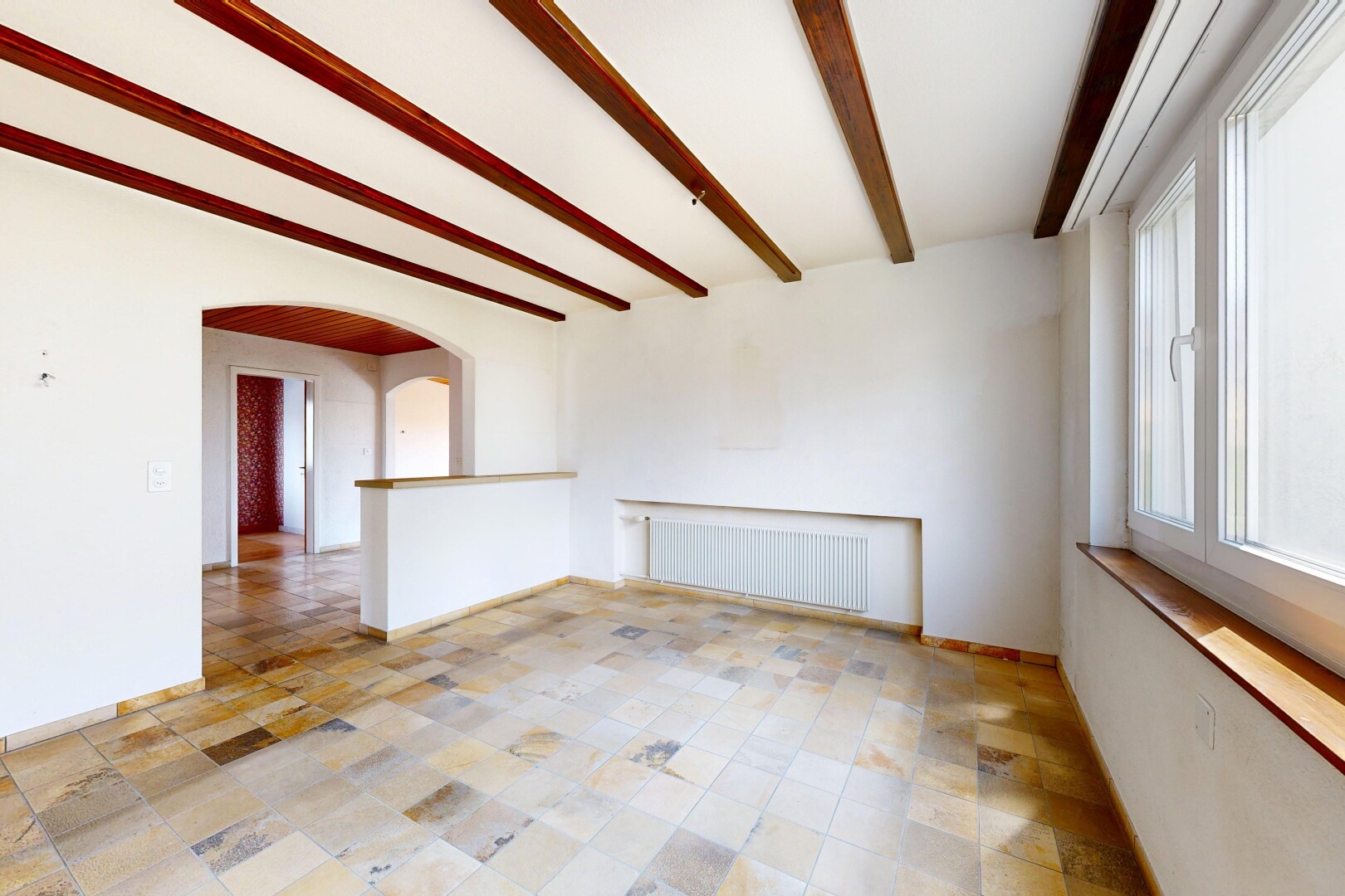 spare room featuring beamed ceiling, radiator heating unit, and arched walkways