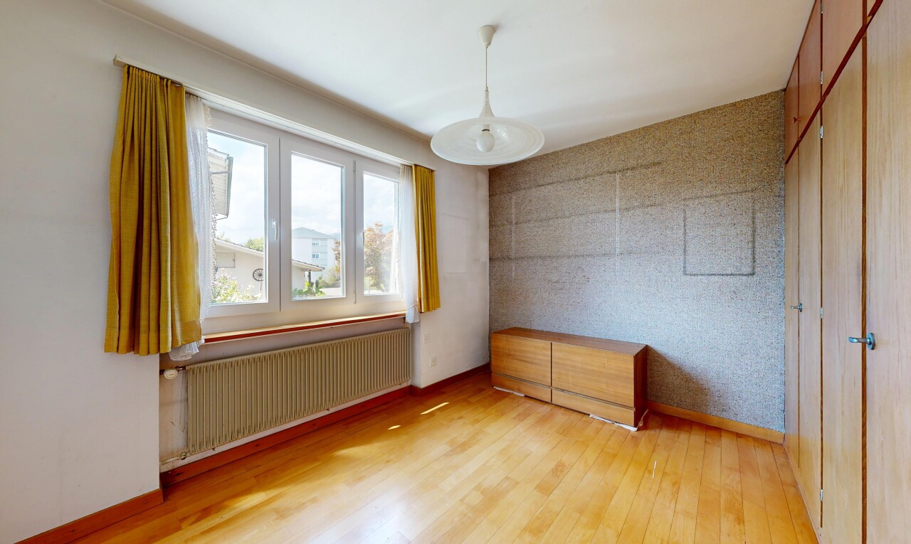 spare room featuring radiator heating unit, light wood-style floors, wallpapered walls, an accent wall, and decorative light fixtures