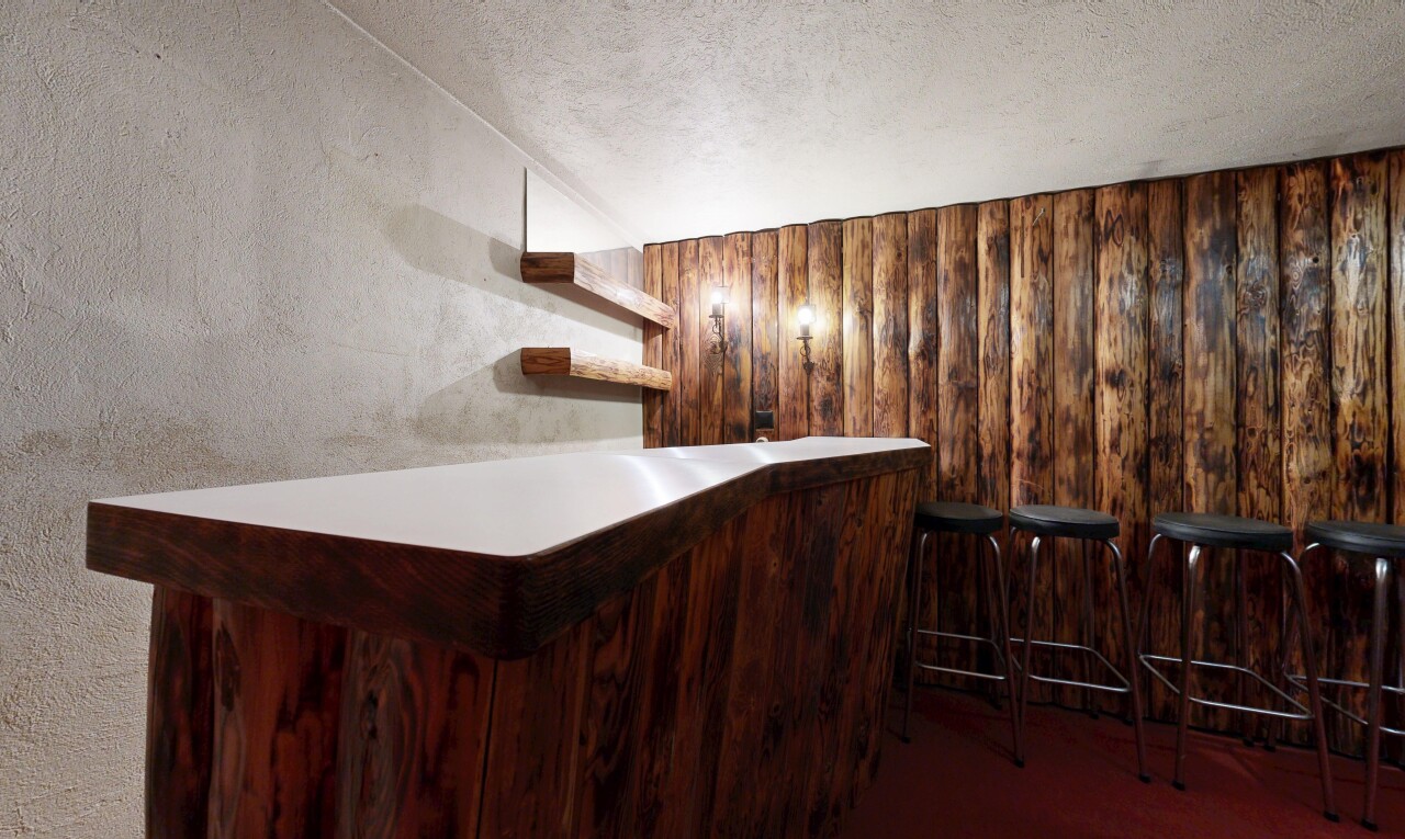 staircase featuring a bar, built in features, wooden walls, and a textured ceiling