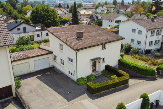view of property featuring a residential view, a garage, driveway, a chimney, and stucco siding