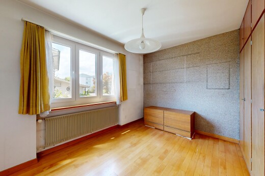 spare room featuring radiator heating unit, light wood-style floors, wallpapered walls, an accent wall, and decorative light fixtures