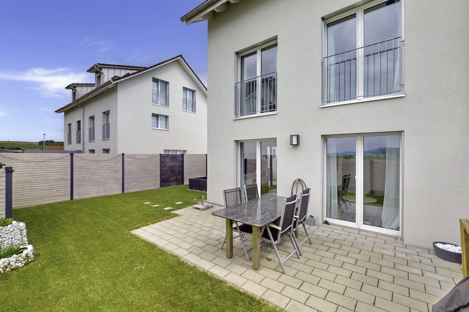 façade avec pelouse, clôture, terrasse, bardage en stuc, et property visible