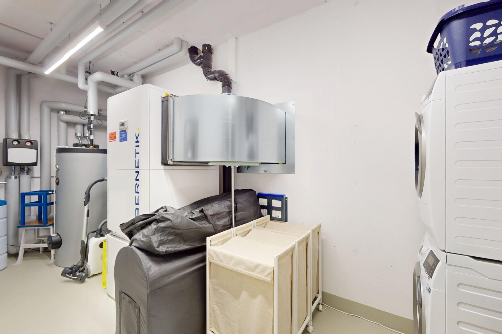buanderie avec inside property, chauffe-eau, lave-linge et sèche-linge superposés, drywall, et cloison sèche
