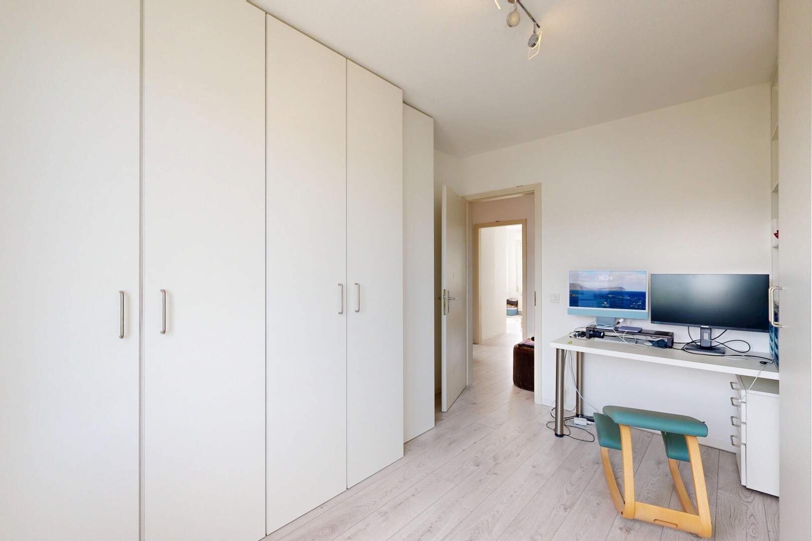 bureau avec wood finish floor, sol en finition bois, éclairage sur rail, télévision, et light floor