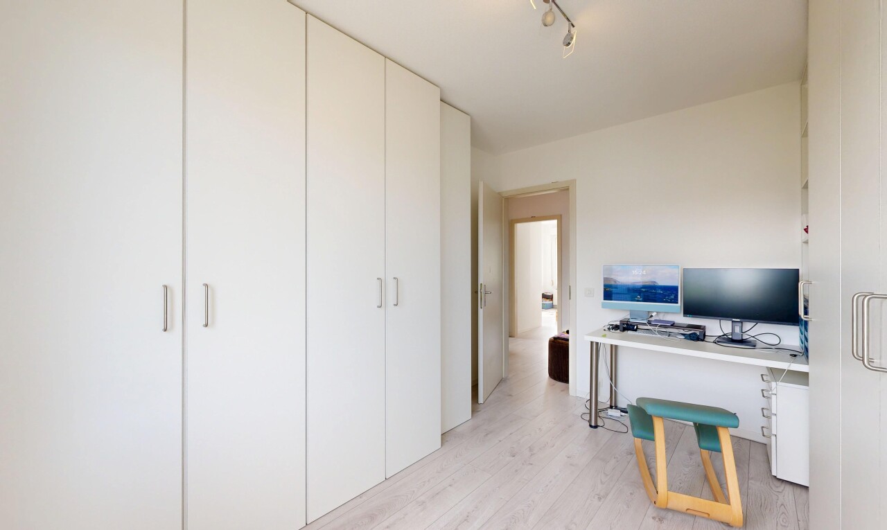 bureau avec wood finish floor, sol en finition bois, éclairage sur rail, télévision, et light floor