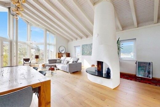 living / dining area featuring vaulted ceiling, light wood finished floors, plenty of natural light, and a lit fireplace