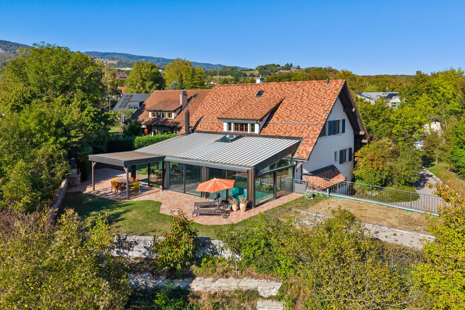 façade avec terrasse, drone view, clôture, toit en métal, et property visible