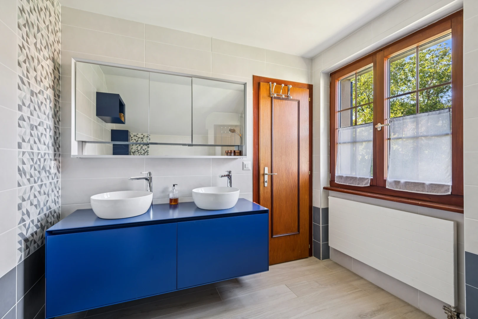 salle de bains avec mur en carrelage, tile wall, radiateur, double vasque, et évier
