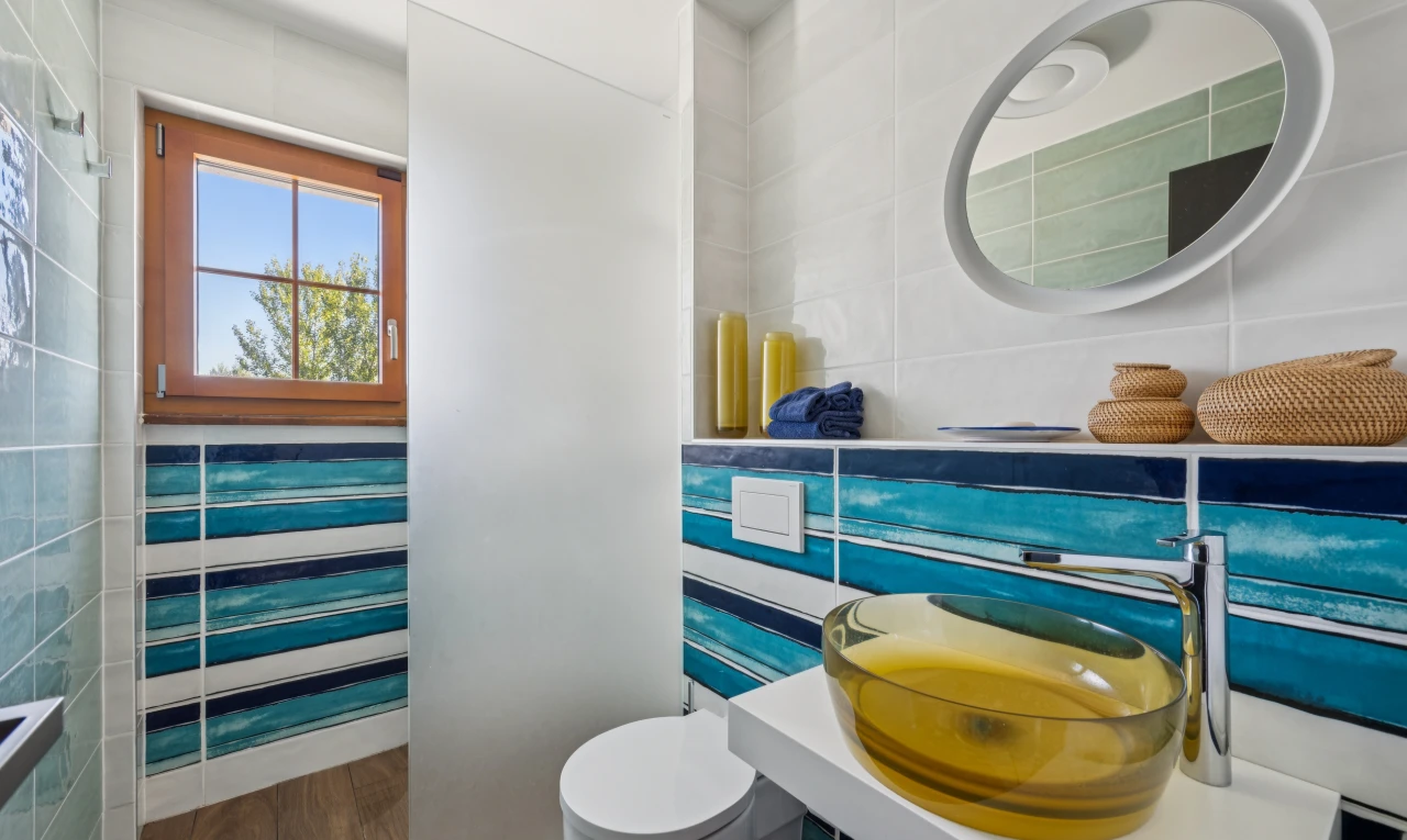 salle de bains avec miroir, mur en carrelage, tile wall, évier, et day time