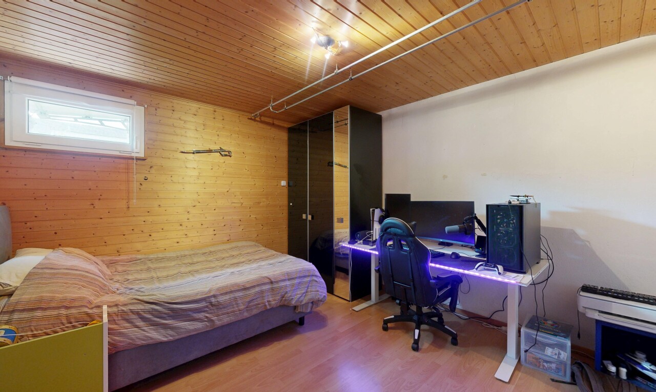 chambre avec espace bureau, sol en finition bois, wood finish floor, mur en bois, et wood wall