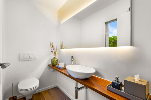 salle de bains avec évier, miroir, toilette, sol en finition bois, et wood finish floor