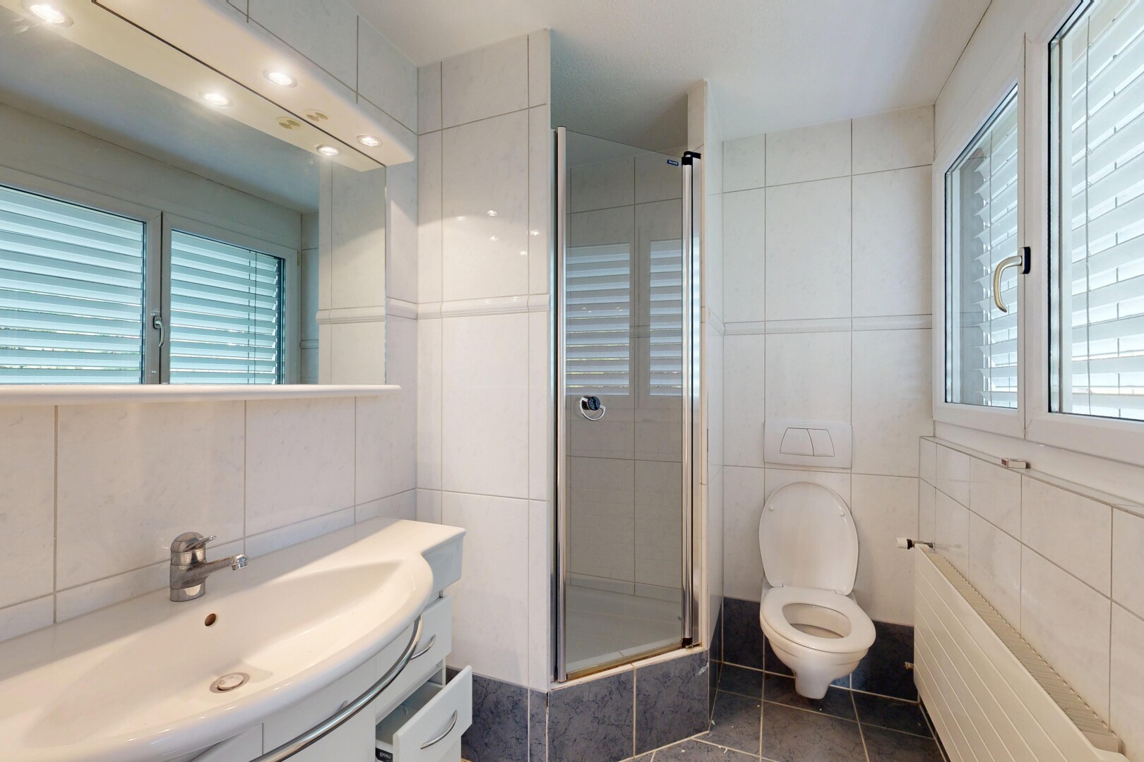 salle de bains avec mur en carrelage, tile wall, radiateur, lavabo (ou coiffeuse selon le contexte), et salle de bain complète