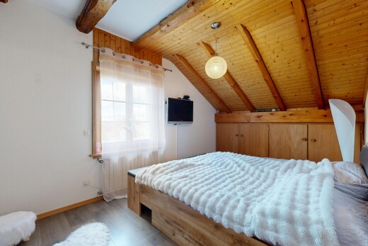 zimmer / schlafzimmer mit gipskartonwand, fernseher, holzfußboden, dachschräge, und balkendecke