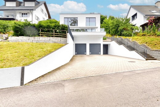 outdoor house featuring a garage, stucco siding, decorative driveway, and a lawn