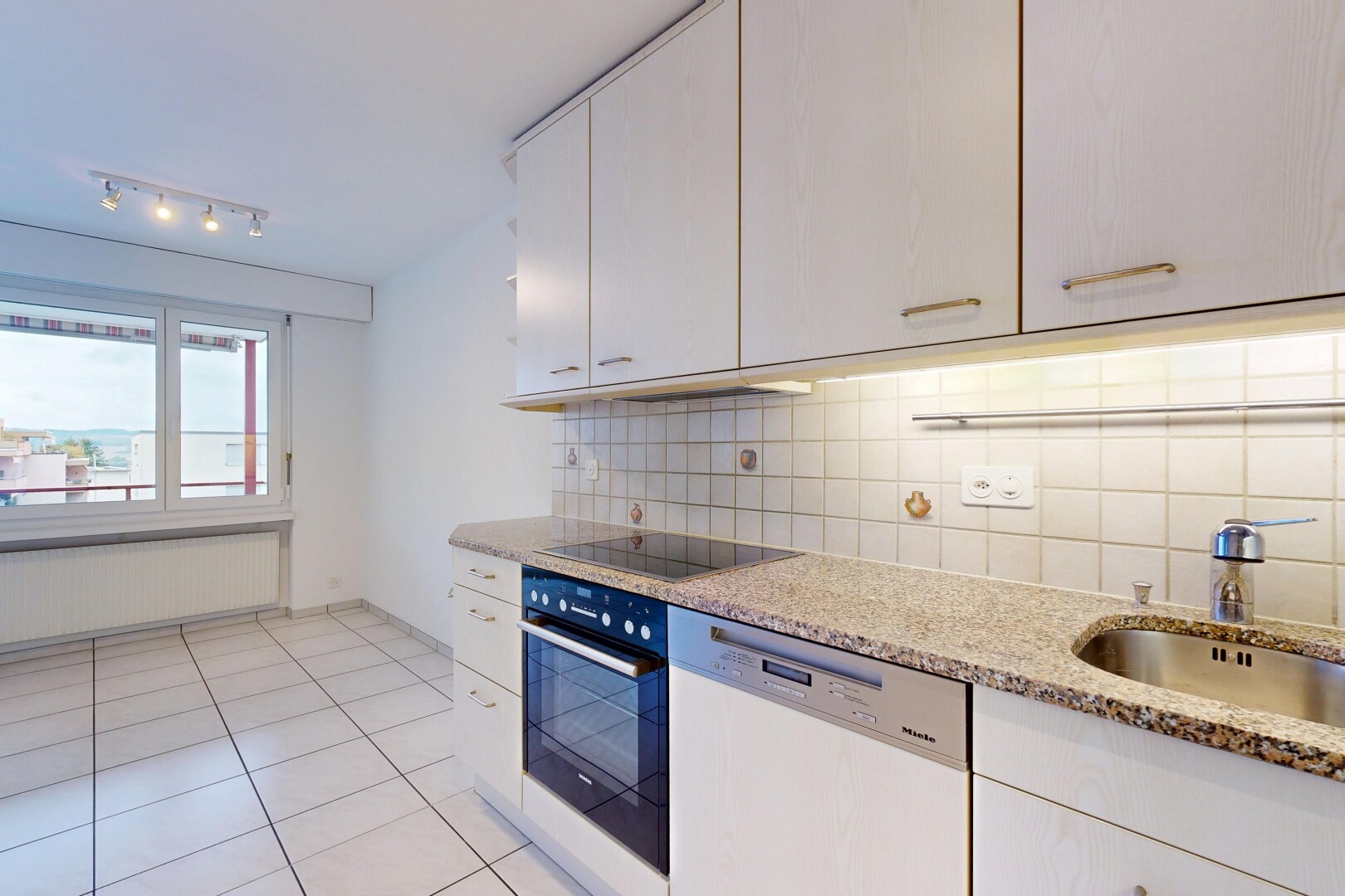cuisine avec éclairage sur rail, light floor, lave-vaisselle, light countertops, et radiateur